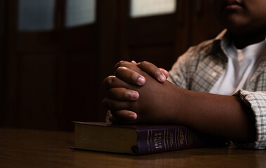 Child Praying with Hands on Holy Bible