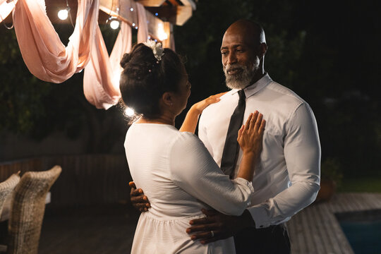 At wedding, Dancing under string lights, senior couple sharing joyful moment at outdoor celebration