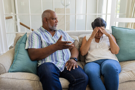 Senior couple discussing serious issue on sofa, woman feeling stressed