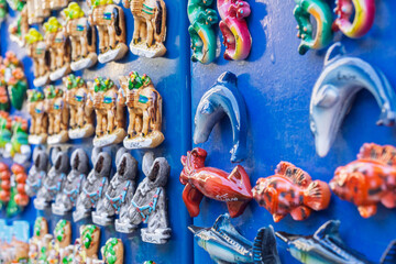 Colorful fridge magnets from Erice, Sicily, Italy,  are displayed on a blue stand