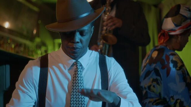 Tilt up slowmo of stylish Black percussionist in vintage attire playing congas during lively jazz performance, surrounded by vibrant ambiance and fellow musicians