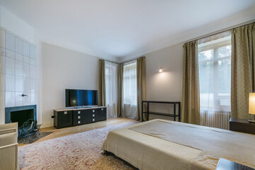 The interior of a spacious bedroom with a fireplace. Beautiful carpet on the parquet floor. Lots of daylight.