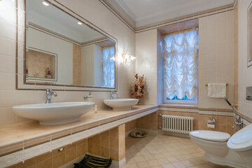 The bathroom is decorated with beige tiles in the Provence style. Stylish accessories, the window is decorated with beautiful drapery.