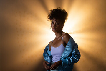African American woman in blue jacket posing confidently with dramatic lighting