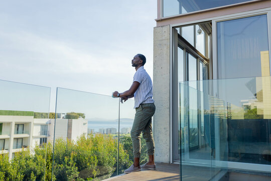 Man enjoying morning view from balcony, relaxing and appreciating cityscape