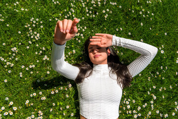 Woman lying on grass in bright sunlight, above view