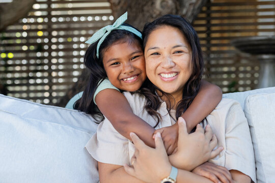 Smiling mother and daughter hugging on couch, enjoying outdoor time together