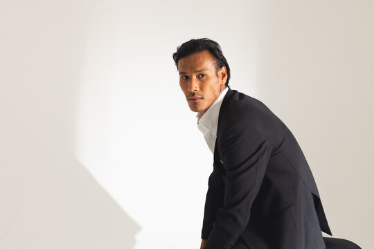 Confident man in stylish suit posing in modern fashion studio
