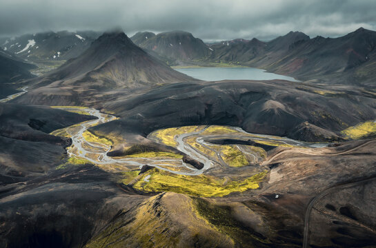 Aerial view of colorful volcanic dramatic landscape in Landmannalaugar during cloudy summer day with picturesque volcanic cones, glacial river and lake. Iceland 