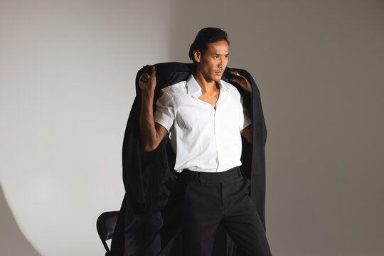 Confident man in stylish suit adjusting jacket in modern fashion studio