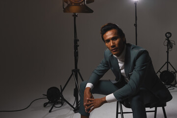 Confident man in stylish suit posing under studio lights, exuding elegance