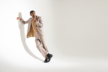 Stylish man in beige suit posing confidently in modern studio setting