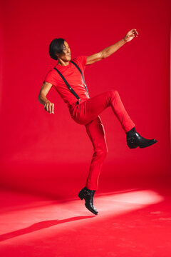 Man in red outfit dancing energetically in studio, expressing joy and movement