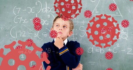 Image of Covid 19 coronavirus cells spreading over thinking schoolboy in class with chalkboard in th