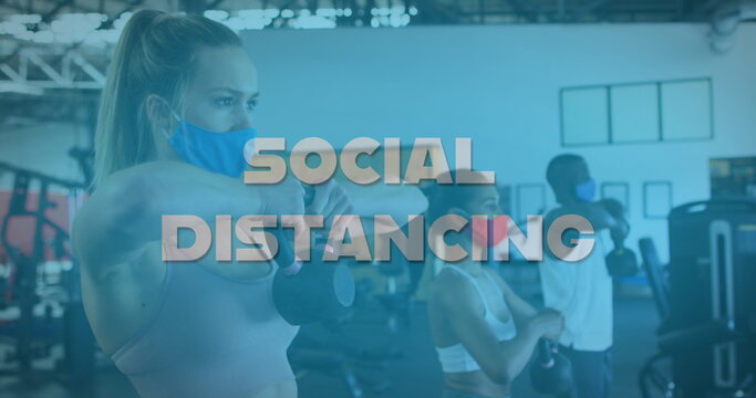 Fototapeta Image of words social distancing over diverse group wearing face masks working out