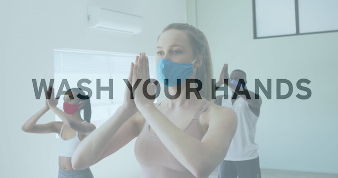 Image of words flashing over diverse group wearing face masks practising yoga