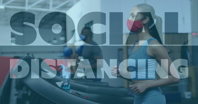 Social distancing against woman wearing face mask running on treadmill at gym