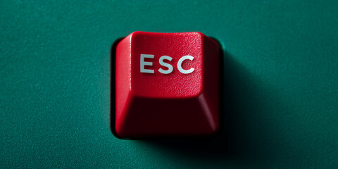 Close-up of red keyboard escape key on teal background, showcasing simple design and functionality, symbolizing exit, interruption or break, suitable for technology or gaming concepts