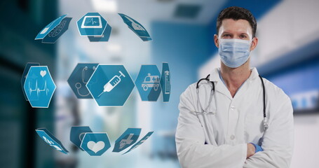 Portrait of caucasian male doctor wearing face mask against globe of medical icons spinning