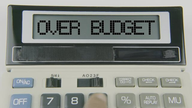 "Over budget" text or words displayed on a calculator's LED screen as a hand types numbers, symbolizing the financial challenge of exceeding allocated funds and the need for better budgeting and cost 