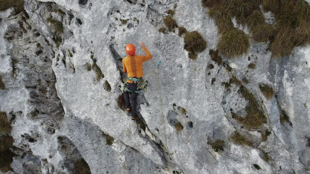 Climber ascending rock wall in scenic outdoor mountain landscape