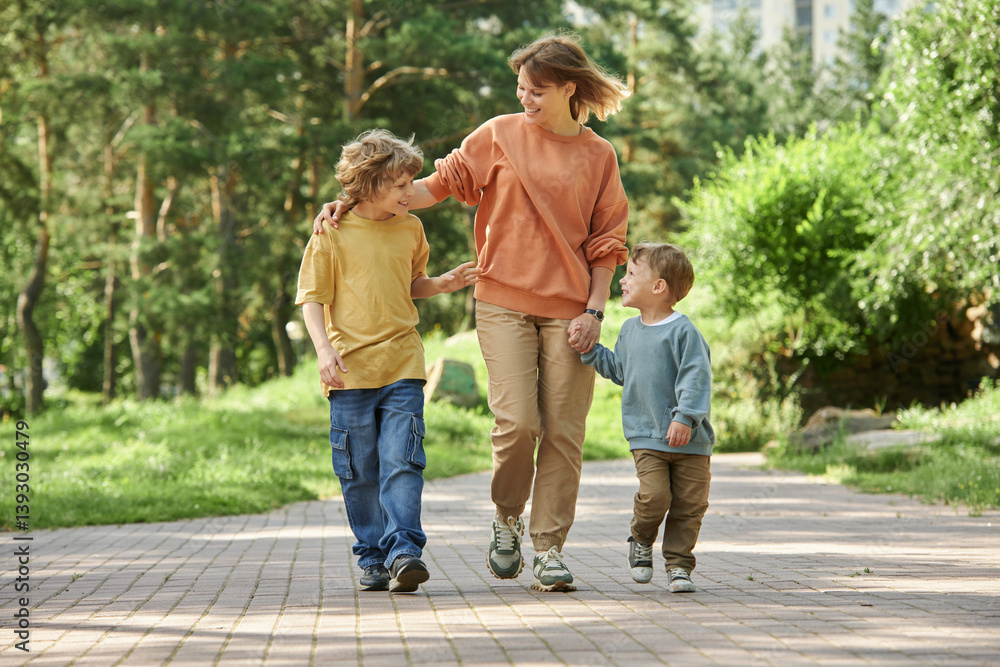 Wall mural full length front view of cheerful mother with two boys holding hands while walking towards camera i