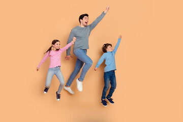 Obraz premium Family bonding concept with father and two children jumping happily against a beige background