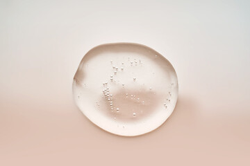 Textured drop of serum with bubbles on pink background.