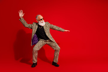 Stylish elderly gentleman in bold leopard print suit striking an energetic pose on vibrant red...