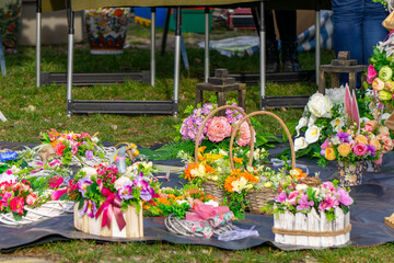 richly decorated Easter baskets displayed on the grass during a holiday fair. The baskets are decorated with flowers, ribbons and greenery, creating a colorful, spring composition.