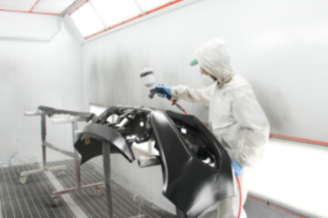 Blurry background Repairman painter hand in protective glove with hand holding airbrush sprinkler painting car body in a paint chamber during repair work