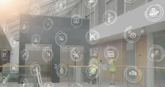 Image of digital icons over architects discussing holding plans - Powered by Adobe
