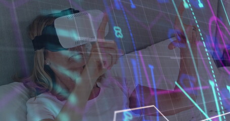 Glowing scope scanning over senior caucasian woman wearing vr headset in bed at home