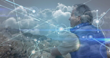 Caucasian senior man hiking sitting admiring view, over network of connections and clouds