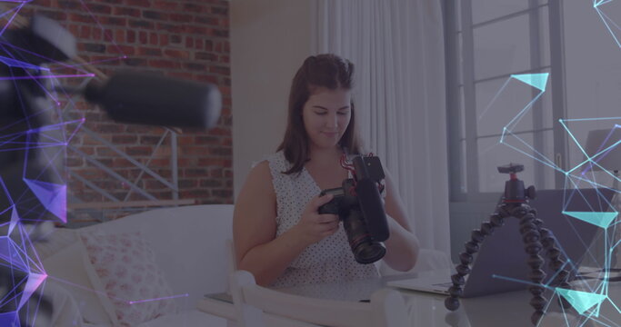 Image of network of connections over female vlogger holding camera recording vlog at home