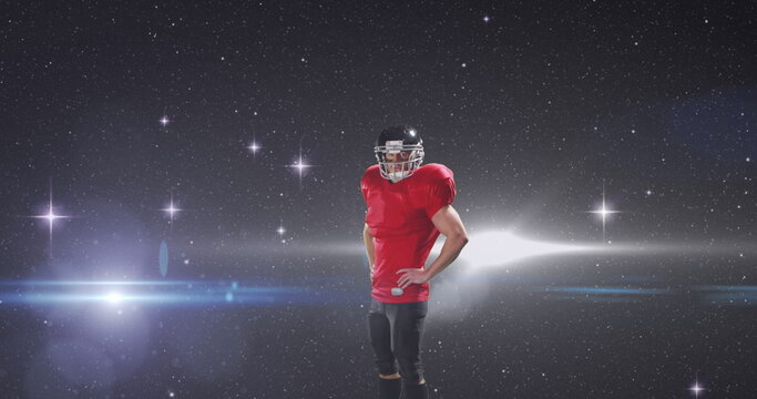 Male rugby player wearing helmet standing against light trails and shining stars in night sky - Powered by Adobe