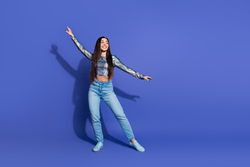 Young woman posing in trendy outfit against vivid purple background