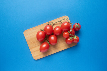 A branch with small tomatoes on a wooden board