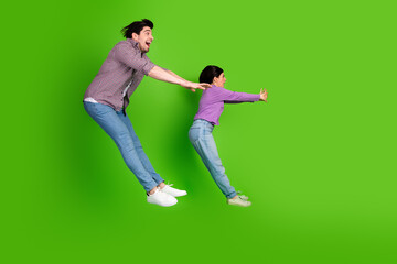 Two young people in casual clothing leaping in a fun dynamic pose on a vibrant green background,...