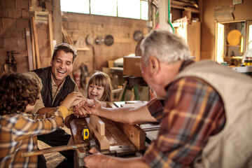 Happy multigenerational family building wooden project together in home workshop
