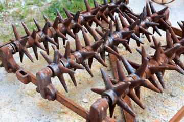 Close up of rusty spiked harrow agricultural farm implement used for surface tillage. Harrow...
