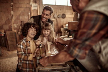 Happy multigenerational family building wooden project together in home workshop