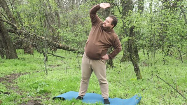 A man does fitness exercises outdoors in the forest.