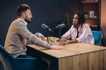 Two podcasters are discussing a topic during a live recording session in a professional studio
