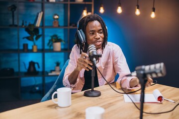 African American man content creator recording his audio podcast using professional microphone and...