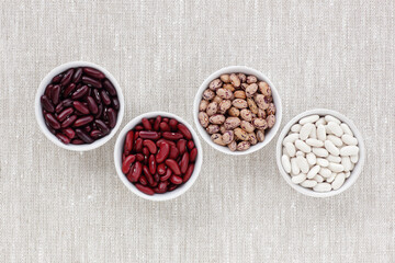 Variety of beans in bowls on textile background from above top view, closeup, copy space, healthy...