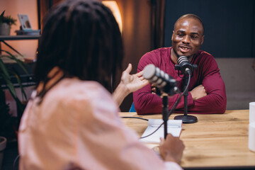 Two men radio hosts, engaging in lively conversation while recording a podcast in a modern...