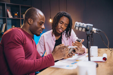 Professional podcasters recording audio content using smartphones and studio microphone