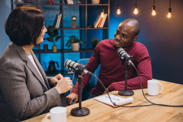 Professional female and male podcasters discussing content, speaking into microphones while...