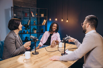 Podcasters recording together, conversing animatedly while seated at studio microphones
